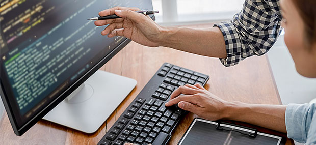 Dos personas colaborando frente a una pantalla con código, simbolizando los servicios gestionados y soporte técnico en Salesforce.